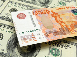 Fototapeta na wymiar Russian banknote of 5000 rubles hangs over a field of American 100-dollar bills