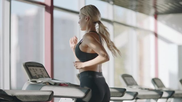 Running woman practicing on treadmill machine in fitness gym.