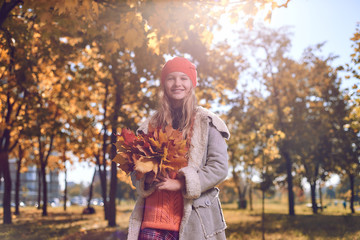 portrait of young girl in red hat and autumn leaves in her hands