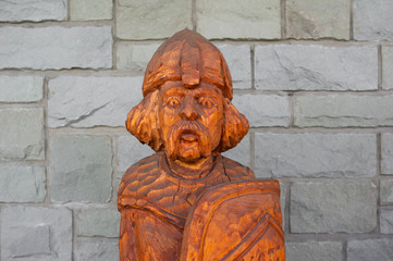 Rustic wooden statue of medieval warrior. Stone background. Low depth of field. 