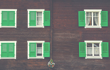 Idyllic impressions and details from the mountain village Ernen. Old wooden brown wall with vintage windows and flowers. Typical wooden house in the alpine canton of Valais in Switzerland.