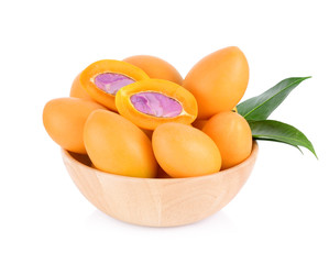 A half of fresh marian plum fruits with leaves in wooden bowl isolated on white background