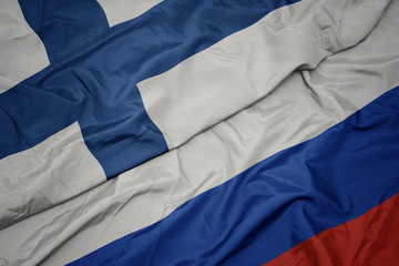waving colorful flag of russia and national flag of finland.