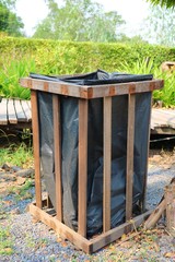 Wooden bin with black bag in the park. Object and environment concept.&nbsp;