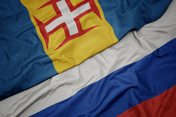 waving colorful flag of russia and national flag of madeira.