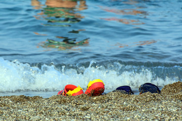 Children's beach shoes stand on the shores of the Mediterranean Sea lit by the sun. Concept - holidays with children