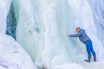 beautiful mature tourist by a frozen waterfall