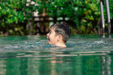Young happy Asian boy spent time with his mother practicing, swimming in swimming pool