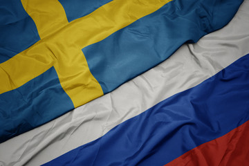 waving colorful flag of russia and national flag of sweden.