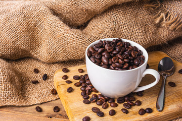 coffee beans in white cup on wooden cutting board