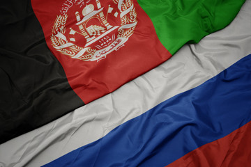waving colorful flag of russia and national flag of afghanistan.