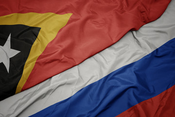 waving colorful flag of russia and national flag of east timor.