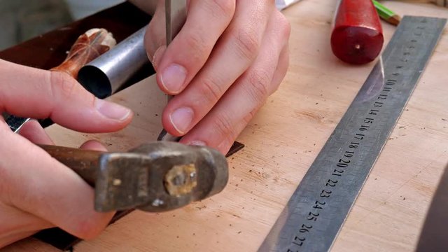 Craftsman making leather wallet. Close up making holes for stitches 