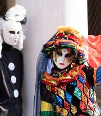 A couple of masks dressed with typical carnival dress, posing for a portrait Piazza in Venice during the traditional carnival.