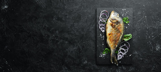 Dorado fish grilled on stone plate. Top view. Free copy space.