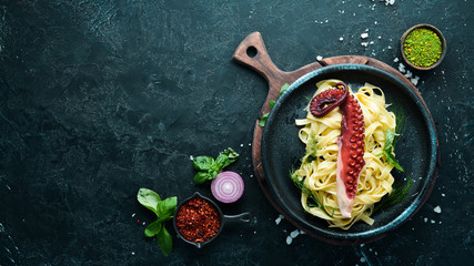 Pasta with octopus on a stone plate. Top view. Free copy space.