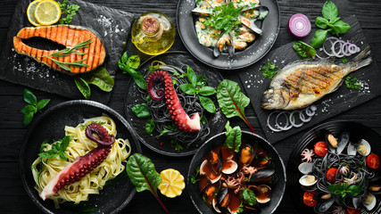 Set of Seafood Dishes. Seafood on a plate. On a black wooden background. Top view. Free copy space.