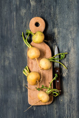 Yellow ripe turnip on a cutting board on a dark wooden background.