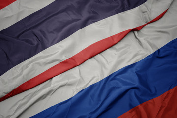 waving colorful flag of russia and national flag of thailand.