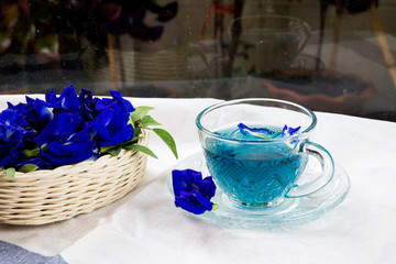 Obraz na płótnie Canvas cup of pea tea and flowers on table