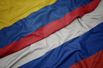 waving colorful flag of russia and national flag of colombia.