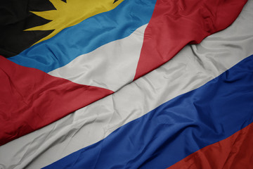 waving colorful flag of russia and national flag of antigua and barbuda.