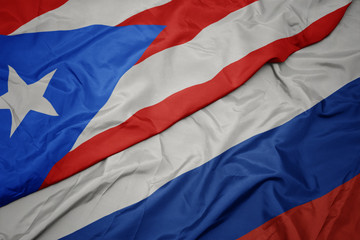 waving colorful flag of russia and national flag of puerto rico.