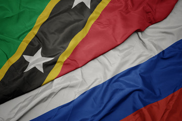 waving colorful flag of russia and national flag of saint kitts and nevis.