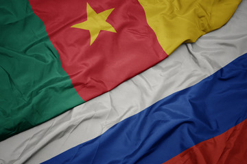 waving colorful flag of russia and national flag of cameroon.