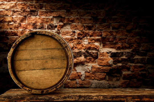 Brown barrel on the brick wall background in a dark cellar.
