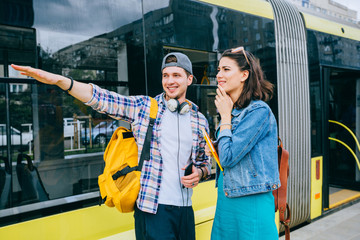stylish male traveler with map in hand asking for help woman with headphones and backpack at subway