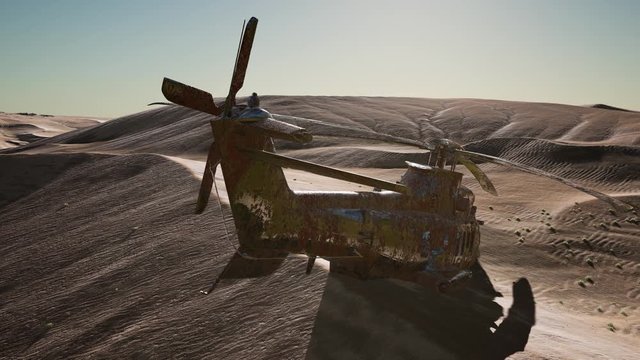 old rusted military helicopter in the desert at sunset