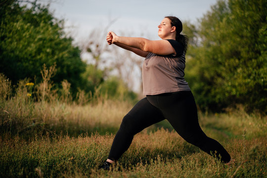 Overweight woman warming up doing exercises before running. Outdoor sports, activity, healthy lifestyle and weight loss