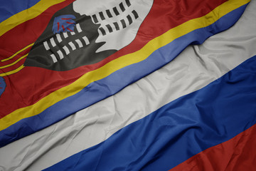 waving colorful flag of russia and national flag of swaziland.