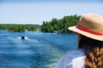 Girl in a straw hat admires a view of a lake with islands