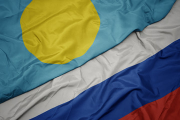 waving colorful flag of russia and national flag of Palau.