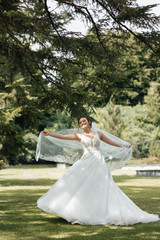 The bride has a white dress with vail. The bride is circling in the nature. Beautiful spring walk...