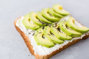 Snacks with avocado. Avocado toast with chia seeds and cream cheese on wooden table. Healthy breakfast lying on gray concrete background. Mockup, flat lay, top view with copy space