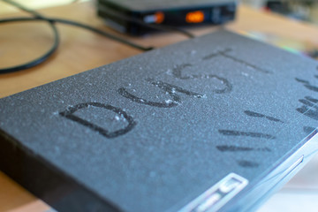 A very dusty DVD player with the word dust written on it with his own dust.