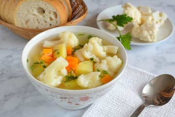 Cauliflower soup with fresh vegetables in a bowl.