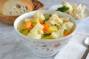 Cauliflower soup with fresh vegetables in a bowl.