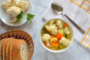 Cauliflower soup with fresh vegetables in a bowl.