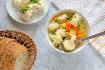 Cauliflower soup with fresh vegetables in a bowl.