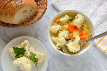 Cauliflower soup with fresh vegetables in a bowl.