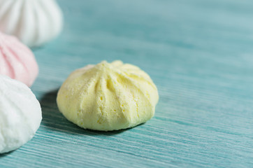 Scattered colored small meringues on light blue background, copy space