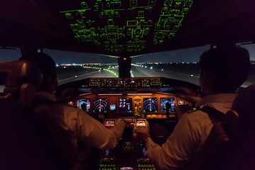 Inside cockpit of commercial airplane after just landed on the runway. Outside window can see beautiful light from airport and inside cockpit can see pilots control airplane. Modern aviation concept.