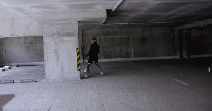 HANDHELD Teenager girl soccer player practicing kicks and moves inside empty covered parking garage. 4K UHD 60 FPS RAW graded footage
