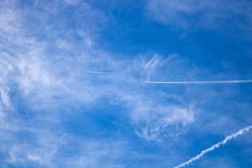 Airplane flying in the blue sky among clouds and sunlight