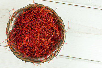 Fototapeta premium Lot of whole red chili pepper threads in old iron bowl flatlay on white wood