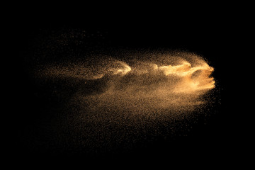 Fototapeta na wymiar Brown particles dust splash on black background. Brown dust explosion.